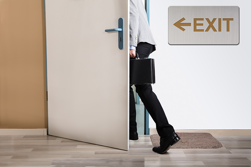 Business Person Walking Out with Exit Sign on Wall